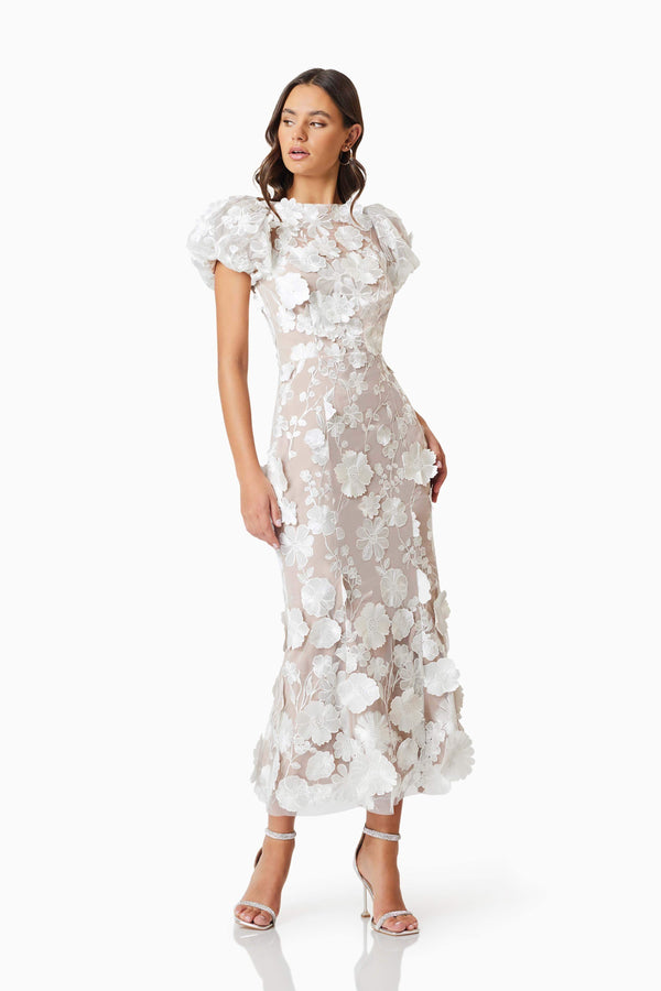 Brunette model wearing Astraea 3D Lace Maxi Dress In White posed looking away shot